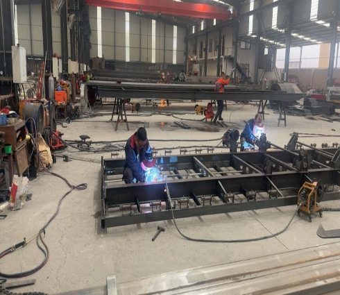 Ouvriers soudant des châssis de semi-remorques dans l’atelier d’un fabricant partenaire